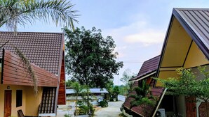 A pathway between two buildings with tiled roofs, surrounded by greenery and a clear sky. - Bansuanphuhong (Chiang Khan)