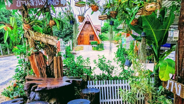 A rustic wooden house surrounded by lush greenery and hanging planters. - Bansuanphuhong (Chiang Khan)