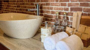 Un baño con un lavamanos grande color beige, un grifo, una botella de jabón para manos, una botella de enjuague bucal y una caja de madera con la etiqueta 'DENTAL KIT'.
