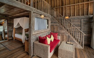 Un interior rústico de madera con una cama, un banco con cojines y una escalera.