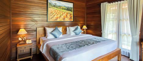 A wooden-paneled room with a large bed, two bedside tables with lamps, a painting on the wall, and a window with curtains.