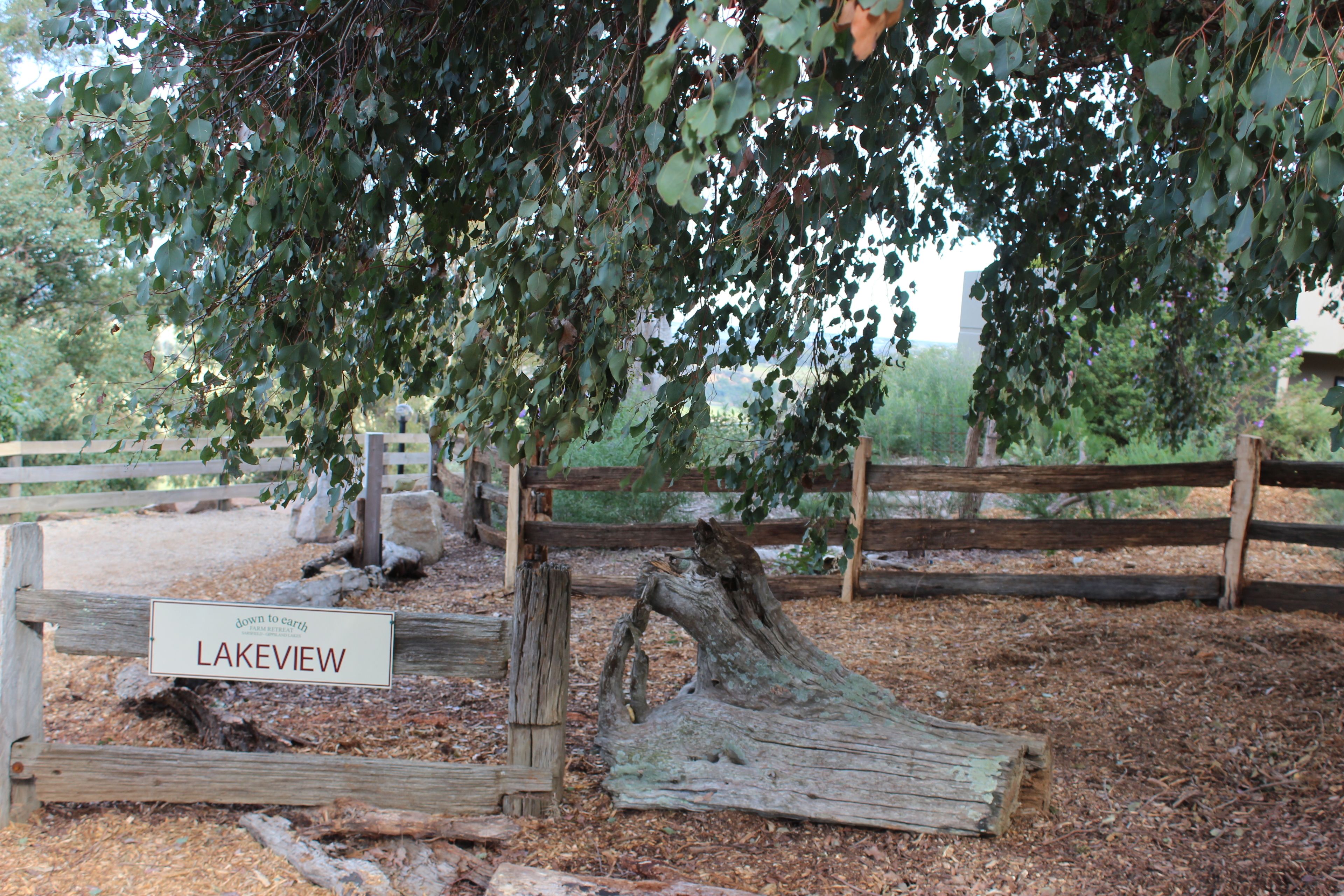 A wooden sign with the text "LAKEVIEW" and a natural landscape with trees and a wooden fence.