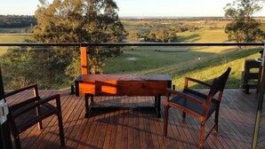 A wooden deck with a table and chairs, overlooking a golf course. - Down to Earth Farm Retreat (Sarsfield)