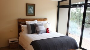 A bed with a wooden headboard, white and gray pillows, and a black quilted blanket. - Down to Earth Farm Retreat (Sarsfield)