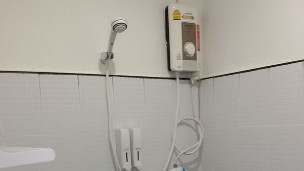 A bathroom with a white sink, a handheld showerhead, and a wall-mounted heater.