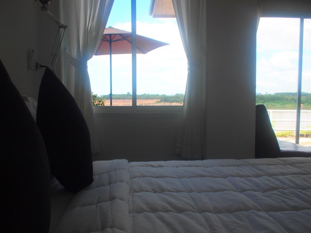 A bedroom with a bed, a window with curtains, and a view of the outdoors.