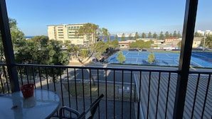 A balcony with a table and chairs, overlooking a parking area and buildings. - Apartment on Tennyson (Port Lincoln)