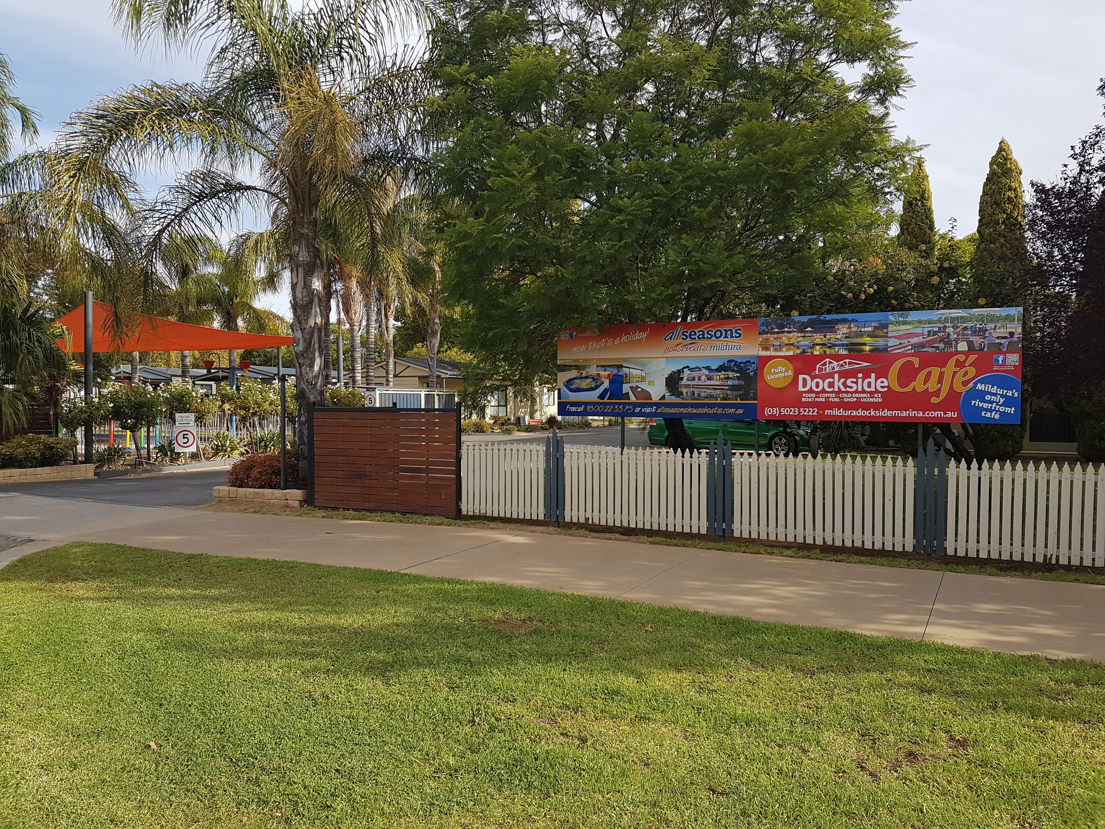 A gated area with a billboard advertising a café and a website for a holiday destination.