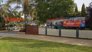 A gated area with a billboard advertising a café and a website for a holiday destination.