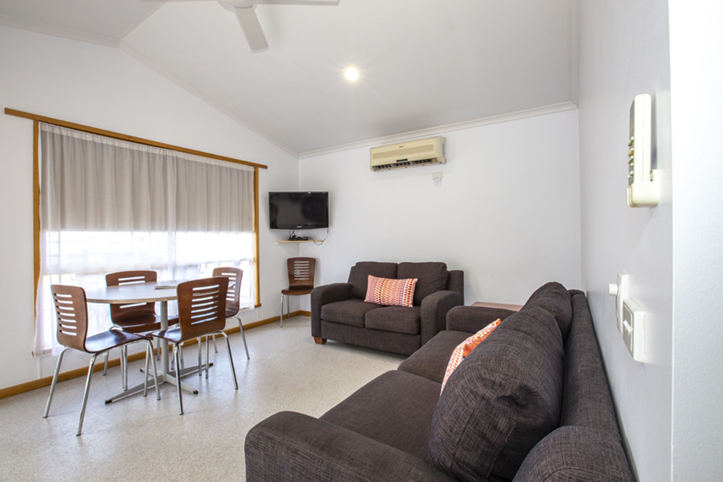 Una sala de estar con sofá, televisor y comedor con sillas y mesa.