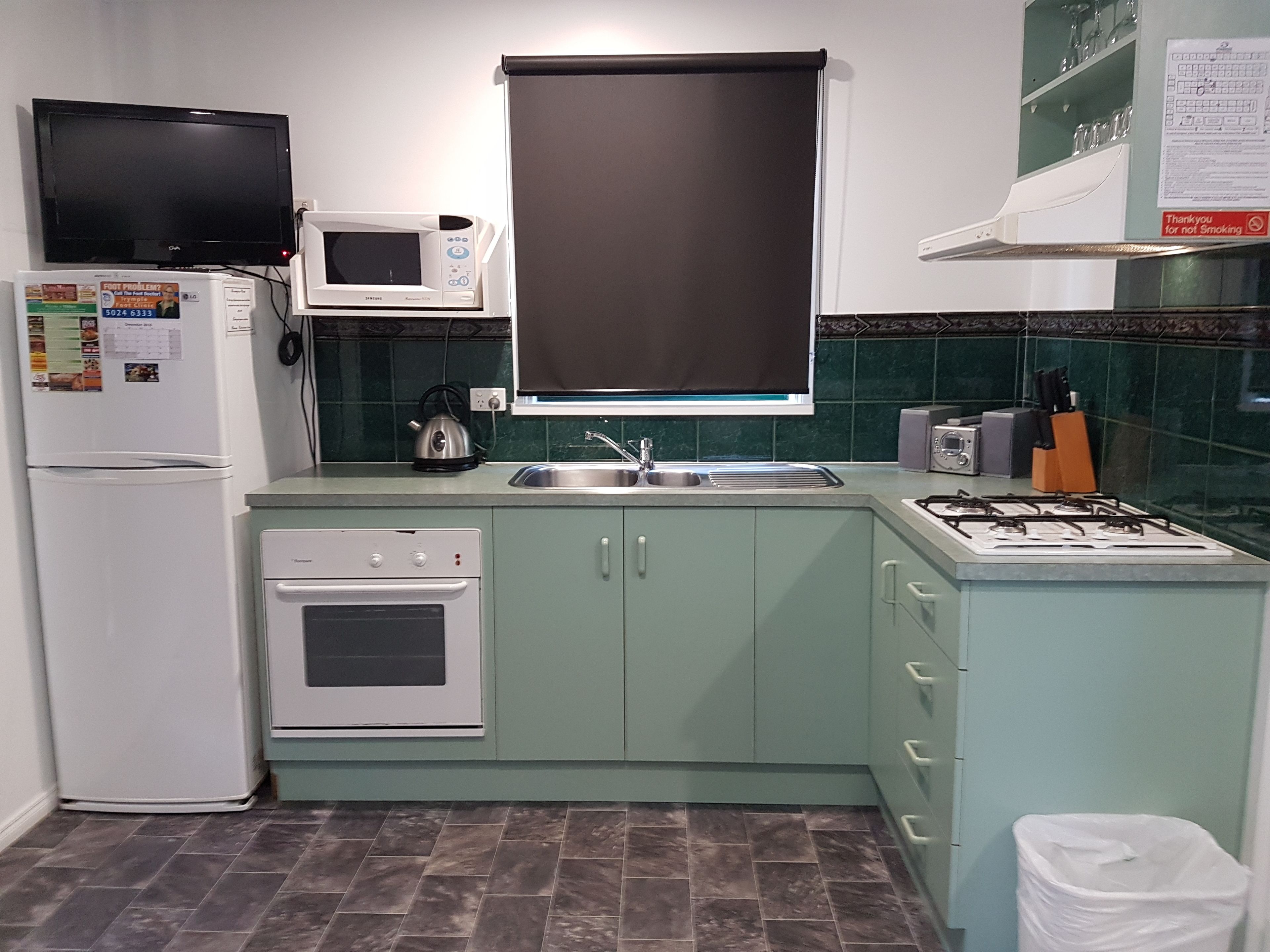 A compact kitchen with a microwave, oven, sink, and gas stove.