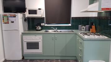A compact kitchen with a microwave, oven, sink, and gas stove.