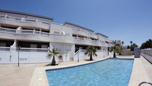 A swimming pool area with a multi-story building in the background. - Apartamentos H3 Laguna Playa (Roquetas de Mar)