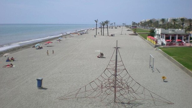 A beach with a large open area, palm trees, and a structure in the center. - Apartamentos H3 Laguna Playa (Roquetas de Mar)