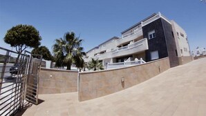 A modern apartment building with multiple balconies, a gated entrance, and palm trees. - Apartamentos H3 Laguna Playa (Roquetas de Mar)