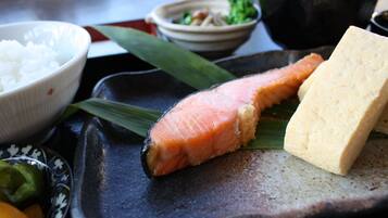 A traditional Japanese meal with salmon, tofu, rice, and pickled vegetables on a ceramic plate.