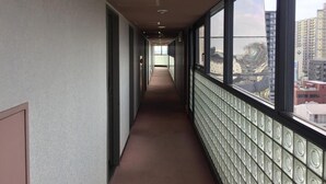 Un pasillo con un revestimiento de pared decorativo y amplios ventanales con vistas a edificios.