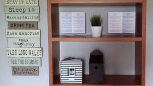 Une bibliothèque remplie de livres et un panneau affichant les règles de la maison.