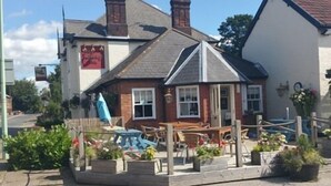 Un petit bâtiment à deux étages, doté d’une façade blanche et d’un toit sombre. Une enseigne sur le bâtiment indique : « The Old Inn ».