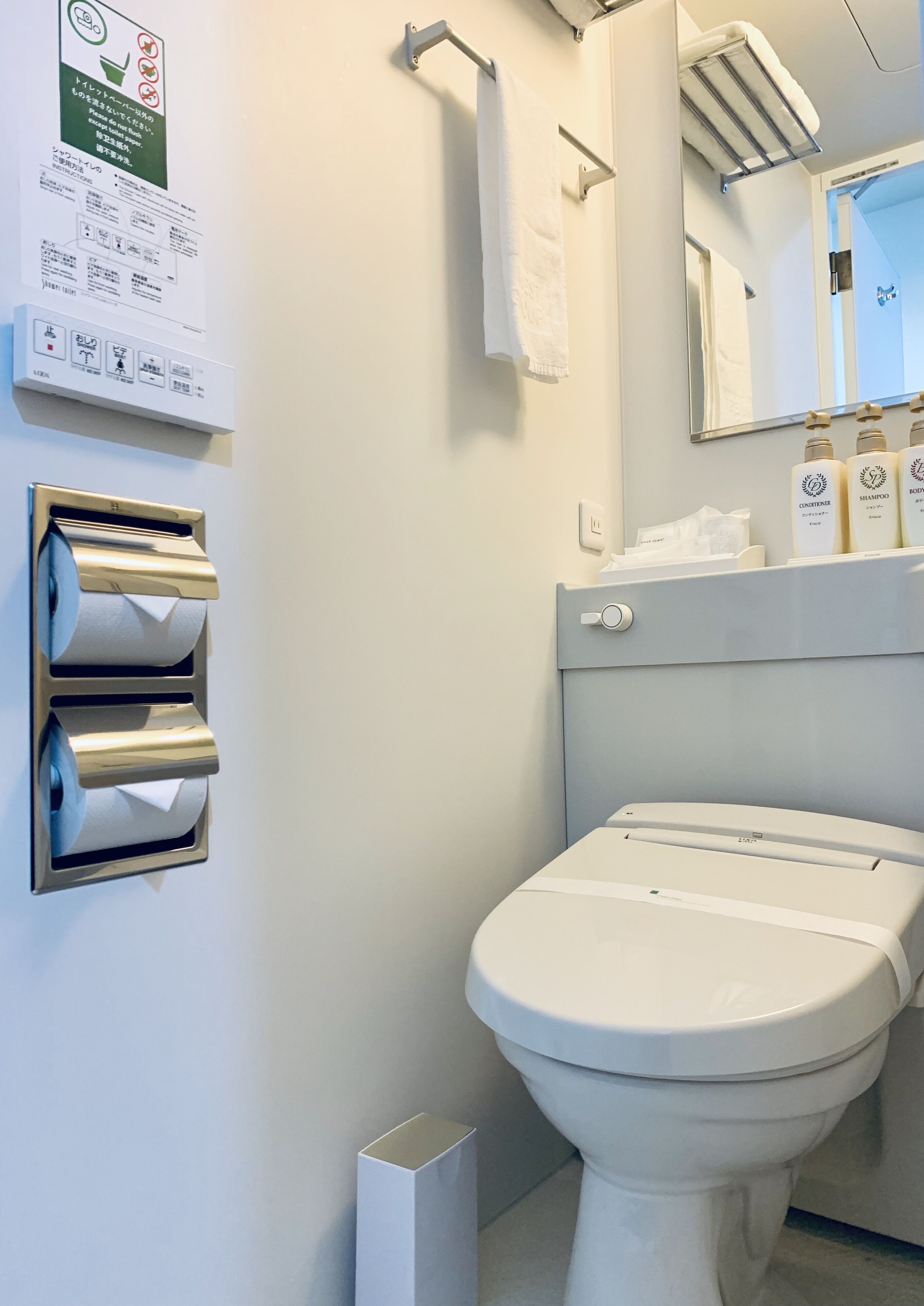 Een moderne badkamer met toilet, papieren handdoekdispenser en handzeep.