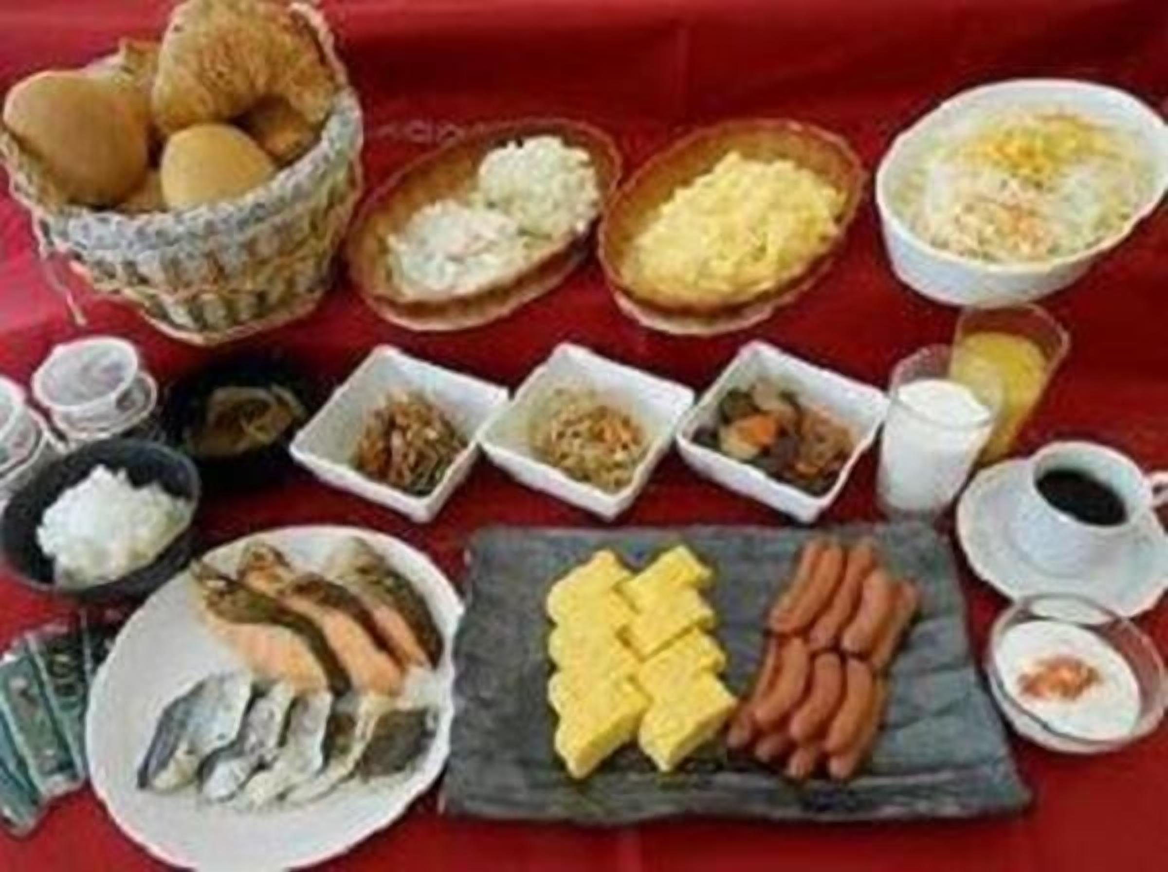 Una mesa con varios platos, incluyendo pescado, salchichas y tazones de arroz.