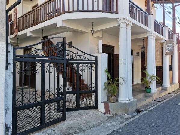 A two-story building with a white facade, a black wrought iron gate, and a balcony with wooden railings. - Southern Comforts - Galle Fort (Galle)