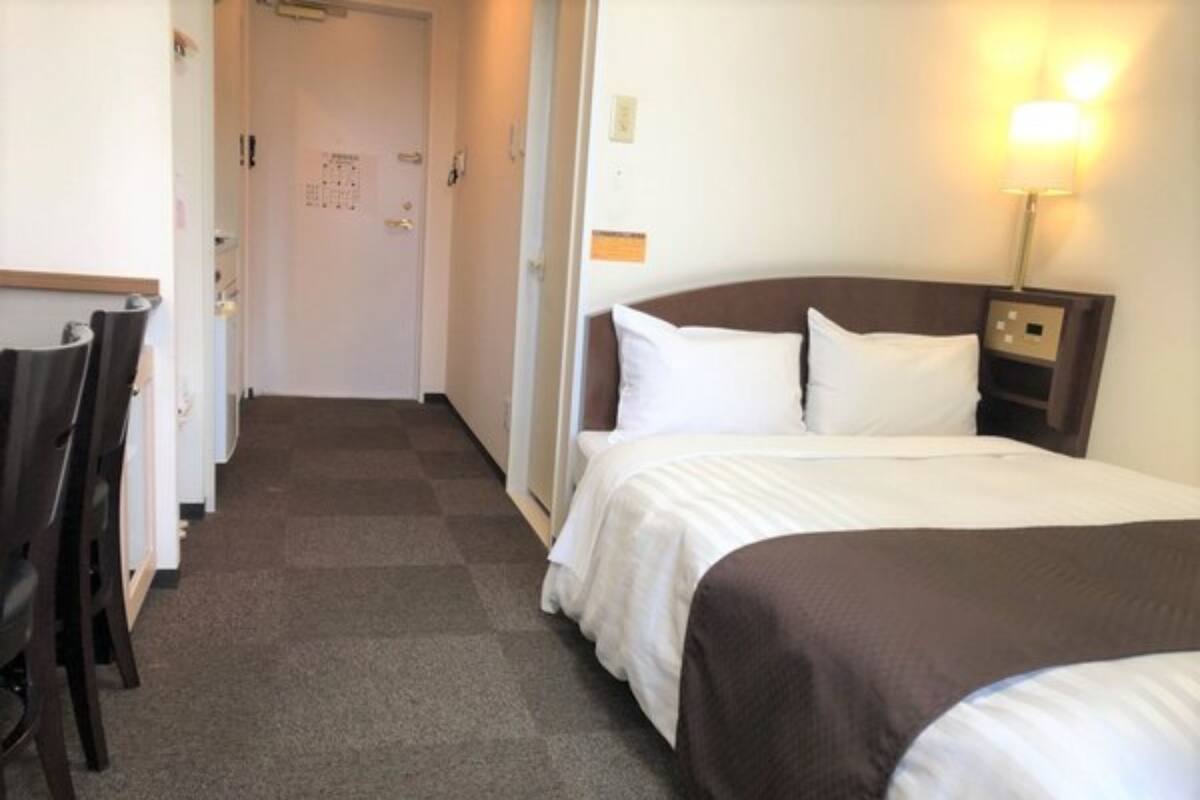 A hotel room with a bed, a desk, and a chair.