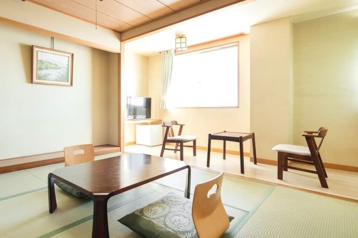 A traditional Japanese room with tatami flooring, a low table, and chairs.