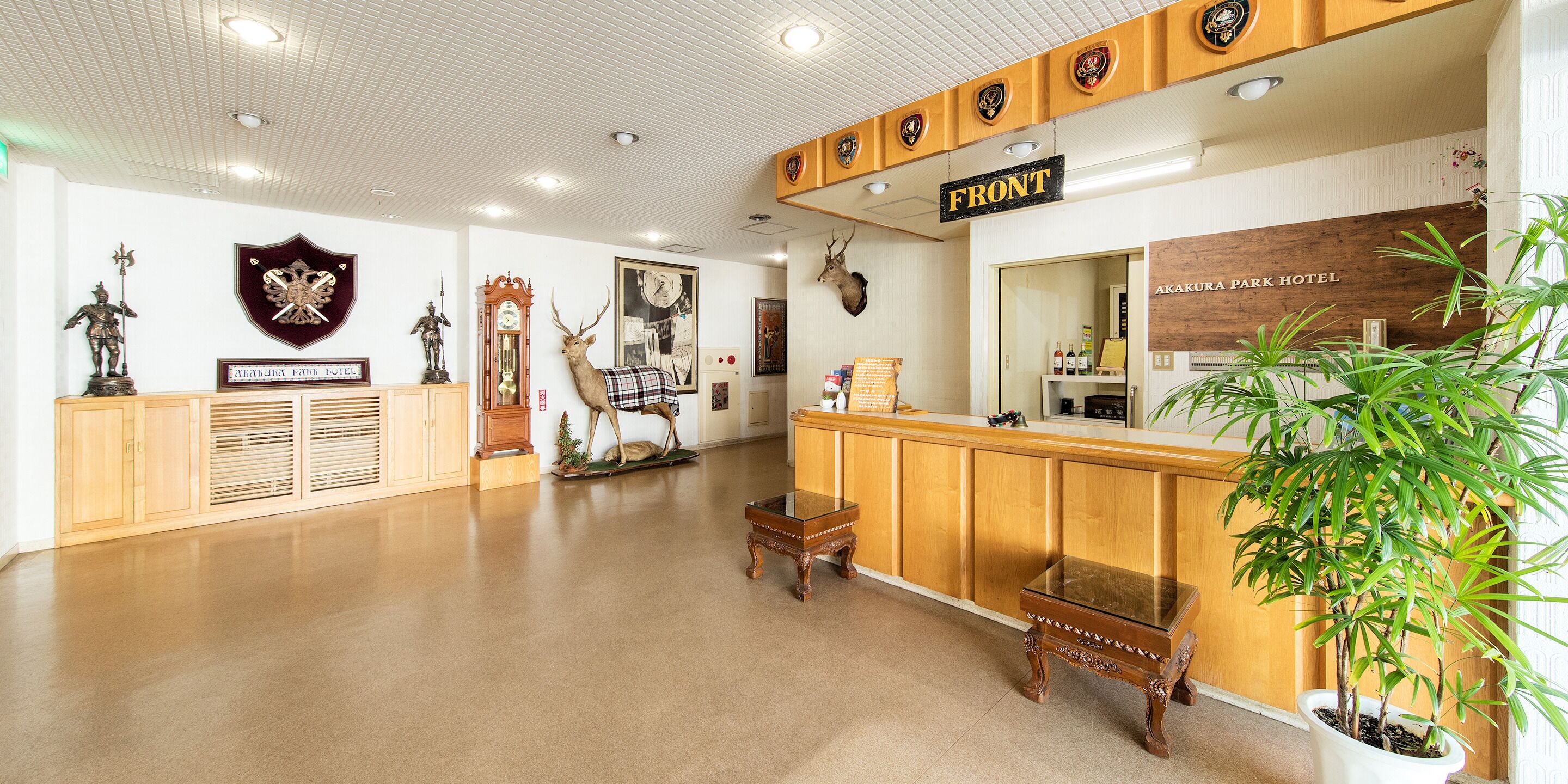 A reception area with a wooden counter, a sign reading "FRONT," and a large potted plant.