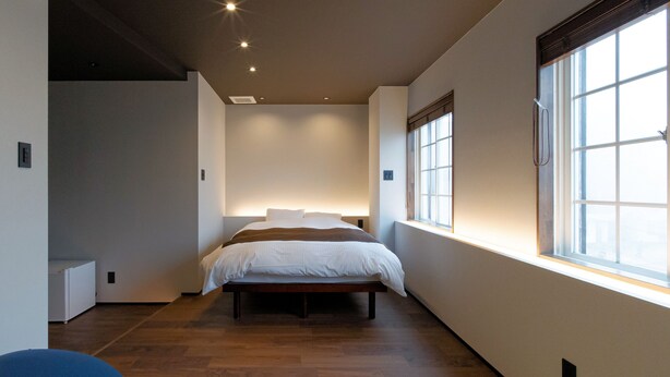 A modern bedroom with a large window, a bed, and a bench. - Yunoyado Mochizuki (Myoko)