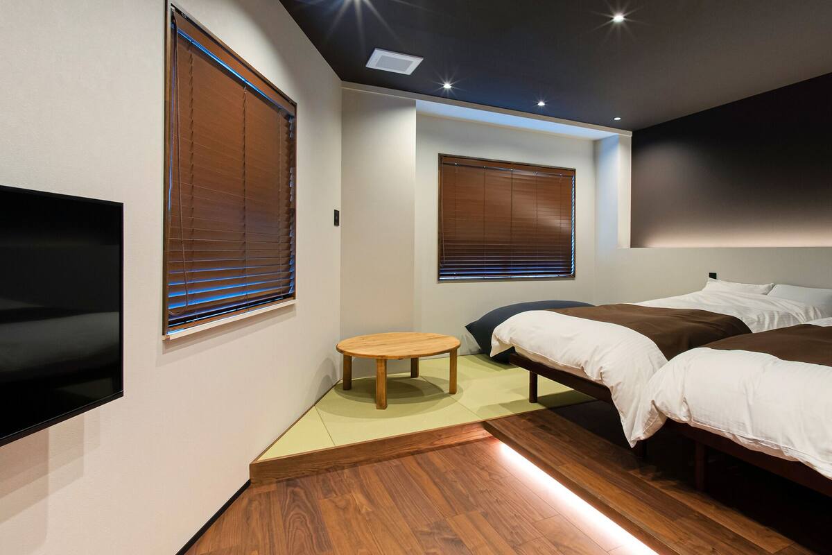 A modern bedroom with two beds, a small wooden table, and a TV.