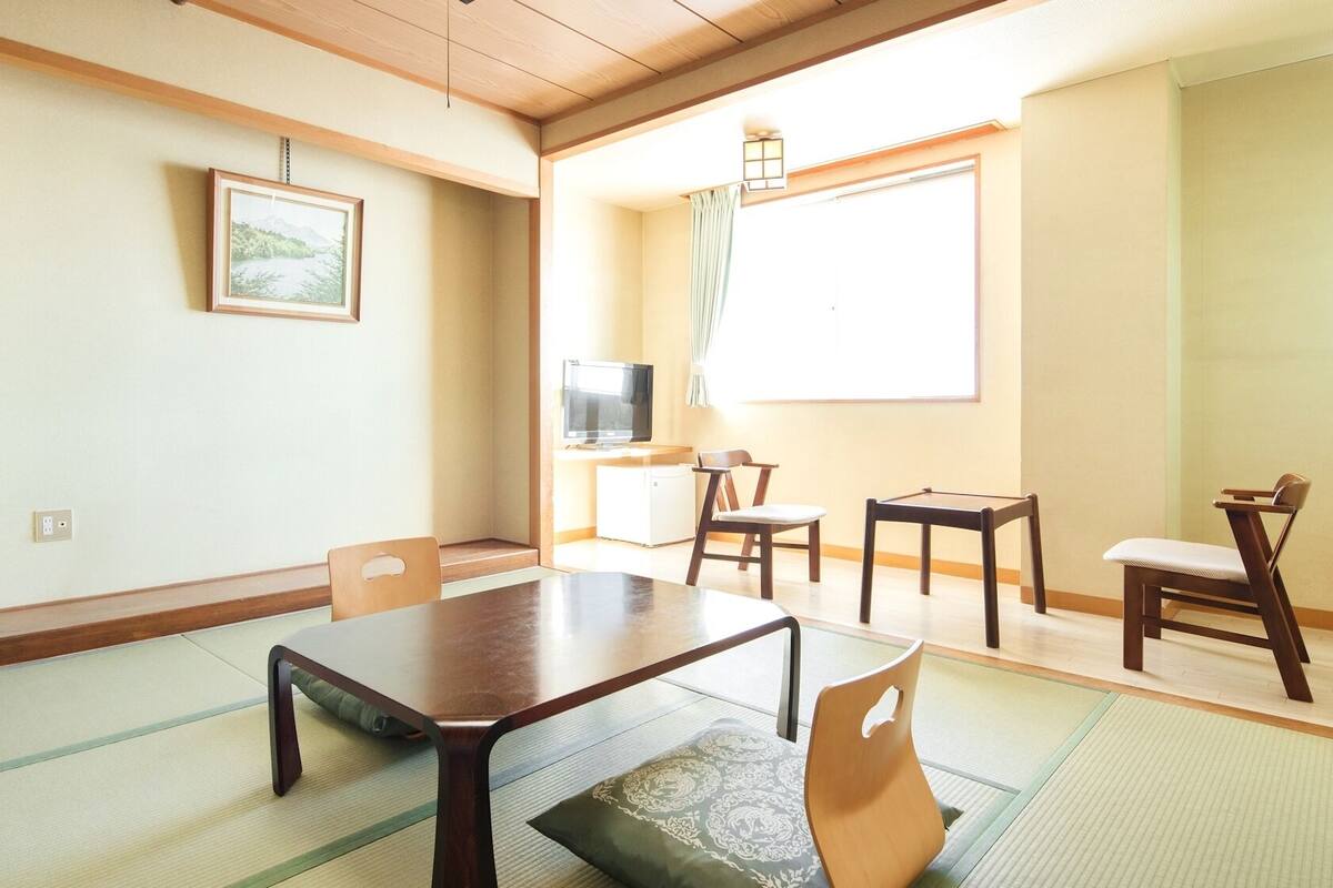 A traditional Japanese-style room with tatami flooring, a low table, and a television.