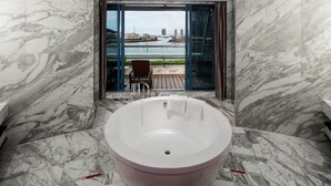 A modern bathroom with a large bathtub, marble walls, and a view of a cityscape through a glass door. - Sanya Visun Royal Yacht Hotel (Sanya)