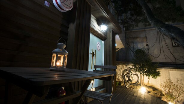 A wooden deck with a table and chairs, a lantern, and a bicycle. - Jeong House (Seoul)