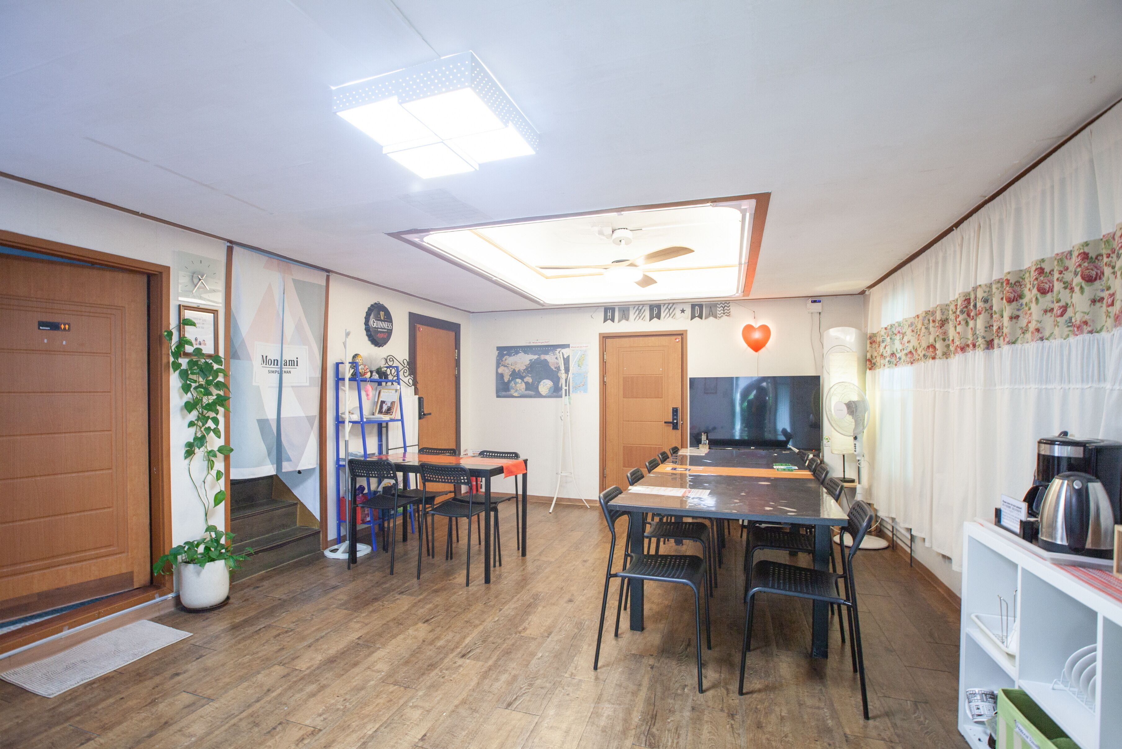 A conference room with a long table, chairs, a ceiling fan, a clock, and a potted plant.