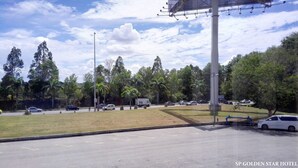 A parking lot with multiple cars, a grassy area, and a large building with a flagpole. - Sp Golden Star Hotel (Sungai Petani)