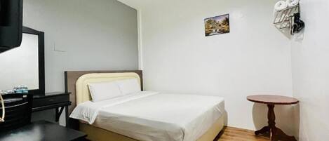 Un dormitorio pequeño y ordenado con cama, escritorio y una mesita.