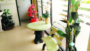 A room with a round table and chairs, a potted plant, and a window with a view of greenery outside. - Sp Golden Star Hotel (Sungai Petani)