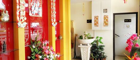 Un vestíbulo de hotel con decoración en rojo y amarillo, una recepción y varias plantas.