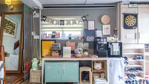 Quarto com cozinha compacta, espelho, relógio e alvo de dardos.