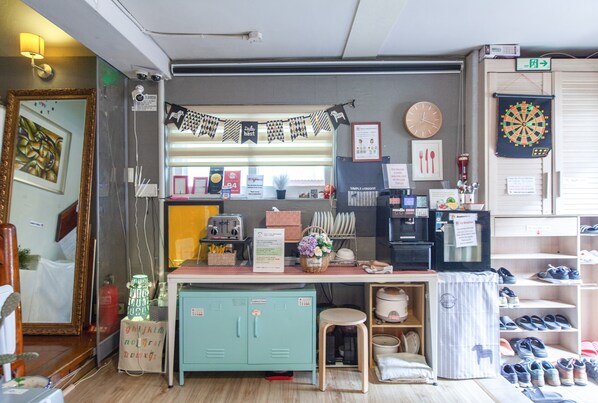 A room with a kitchenette, a mirror, a clock, and a dartboard. - Hongdae Style Guesthouse (Seoul)