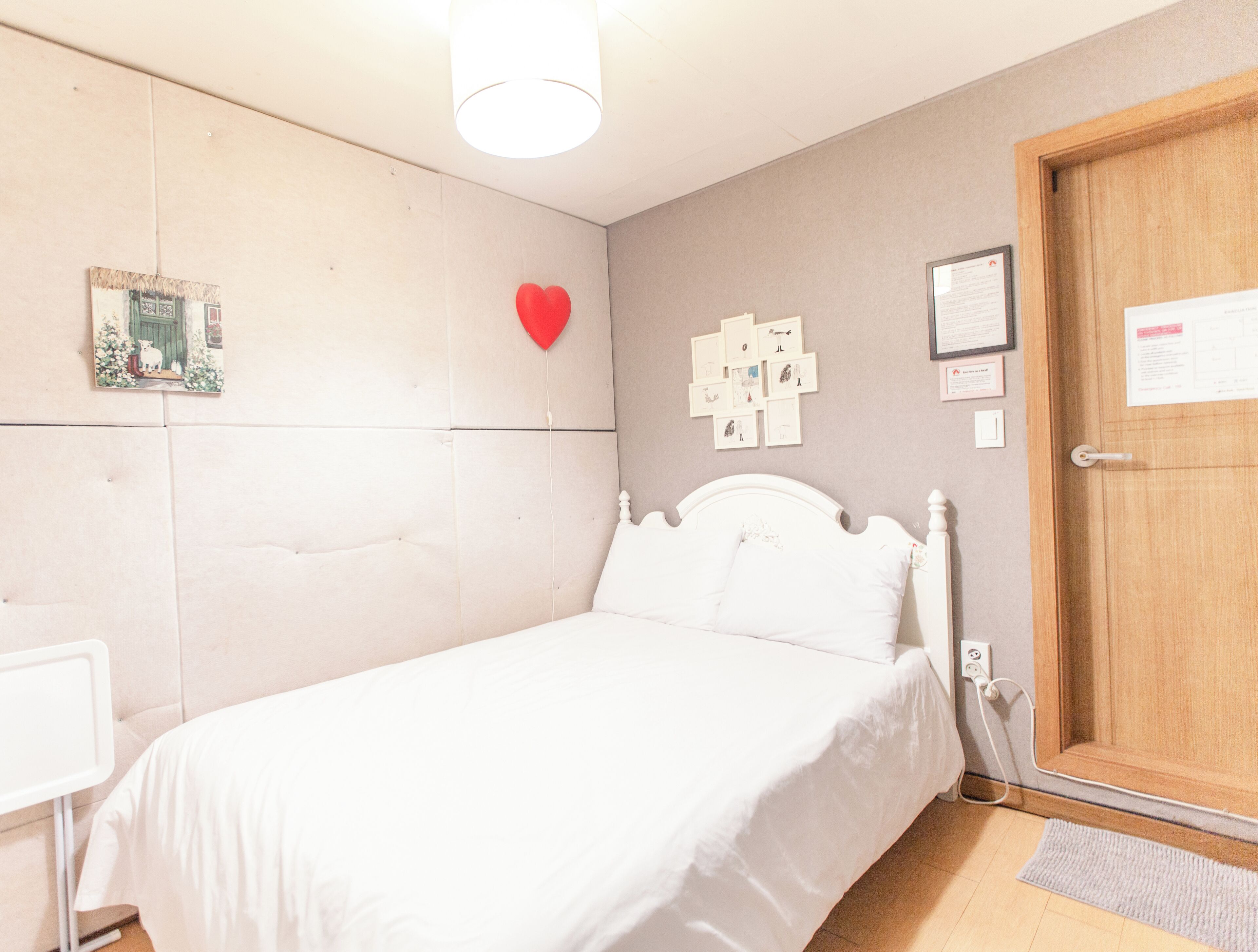 Quarto com uma cama, porta de madeira, luminária e detalhes decorativos nas paredes.