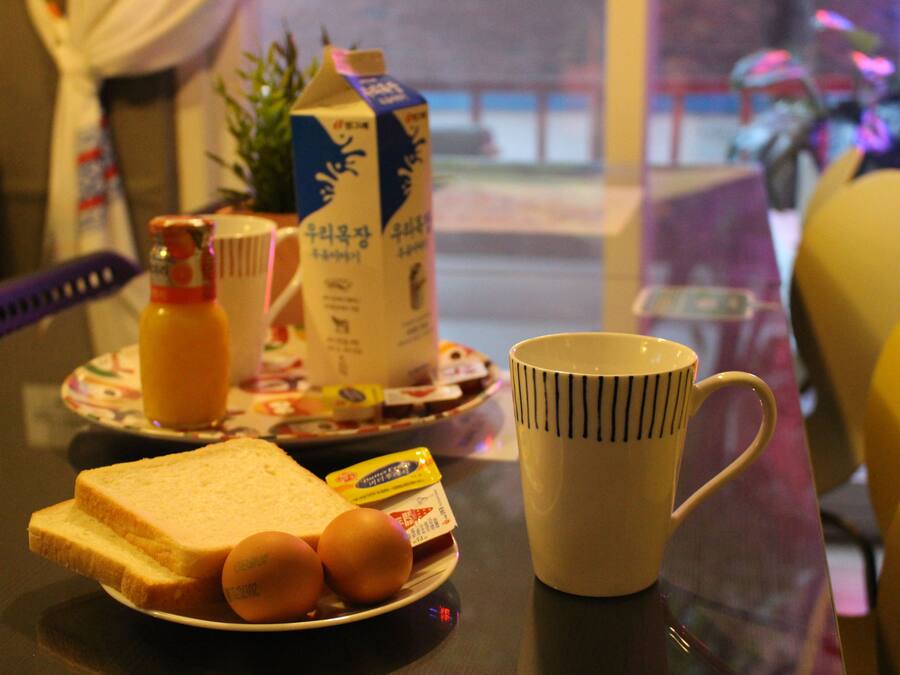 A breakfast table with a plate of toast, eggs, a mug, and a carton of milk.