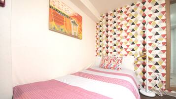 Un dormitorio con una cama, una pared con un estampado geométrico colorido y un cartel en la pared.