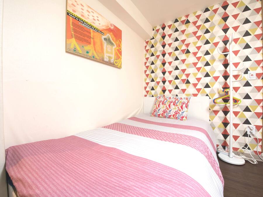 Un dormitorio con una cama, una pared con un estampado geométrico colorido y un cartel en la pared.
