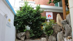 Uma escadaria de pedra leva a um edifício com uma placa que diz 'Hongdae Style Guest House'.
