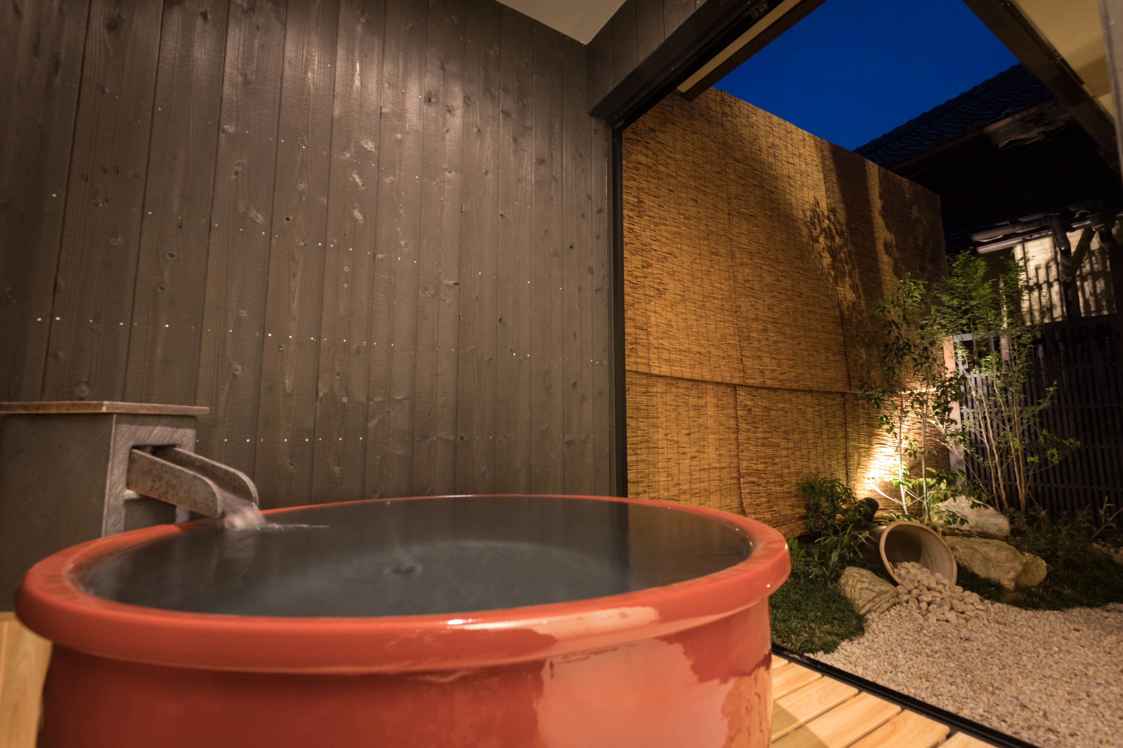 A hot tub with a wooden wall and a brick wall in the background.