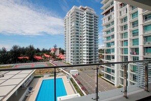 A high-rise residential building with multiple balconies, a swimming pool, and a view of a sports field. - Imperial Suites Miri (Miri)