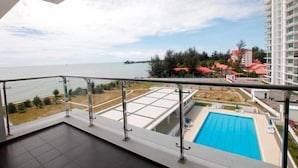 Un balcón con vista a una piscina y una masa de agua distante.
