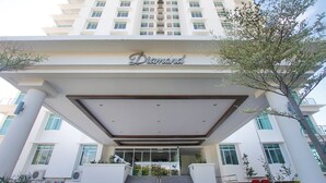 Una entrada de hotel moderna con un letrero llamativo que dice 'Diamond', una escalera cubierta y un gran ventanal.